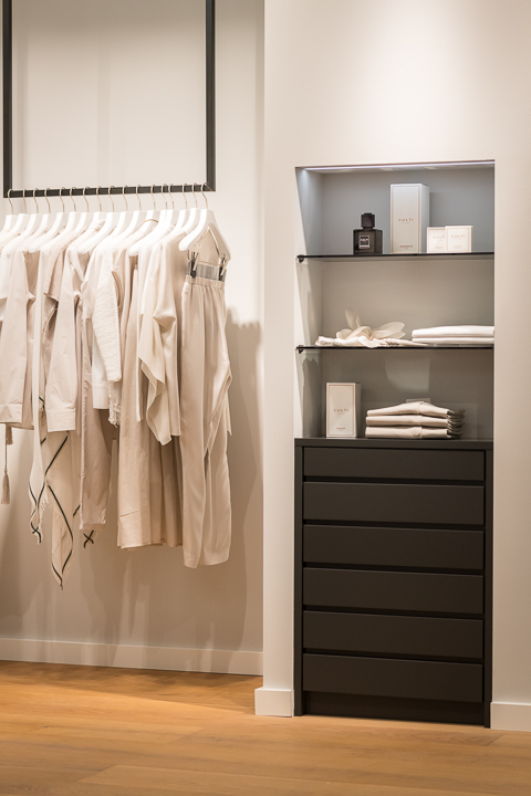 Kleiderstange mit schwarzer Schubladenkommode und Regalen